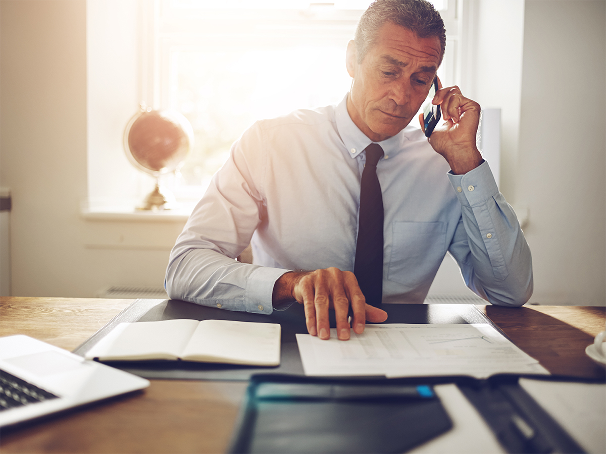 businessman on the phone, looking at papers on the desk